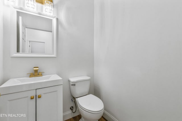 bathroom featuring baseboards, vanity, toilet, and wood finished floors