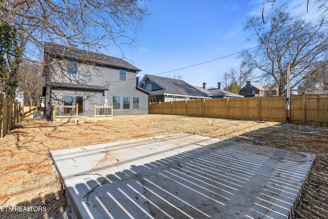 rear view of house with a fenced backyard and a deck