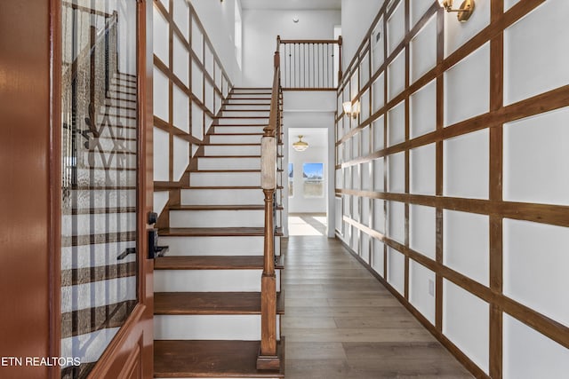 staircase with wood finished floors and a towering ceiling