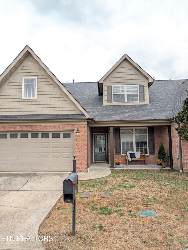 traditional home featuring a garage, covered porch, concrete driveway, and brick siding