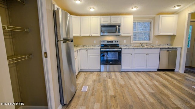 kitchen featuring stainless steel appliances, a sink, and white cabinetry