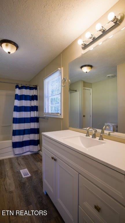 bathroom featuring curtained shower, visible vents, a textured ceiling, vanity, and wood finished floors