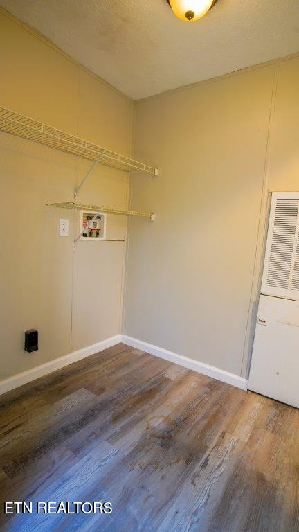 clothes washing area with a textured ceiling, laundry area, washer hookup, wood finished floors, and baseboards