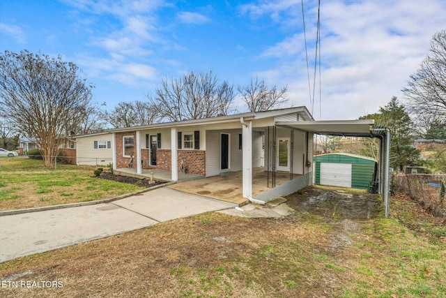 ranch-style house with driveway, an outbuilding, fence, a porch, and brick siding