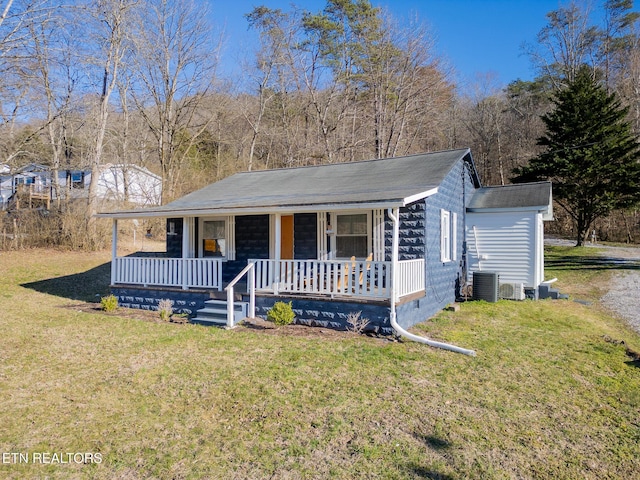 view of front of home with a front yard, covered porch, and central AC unit