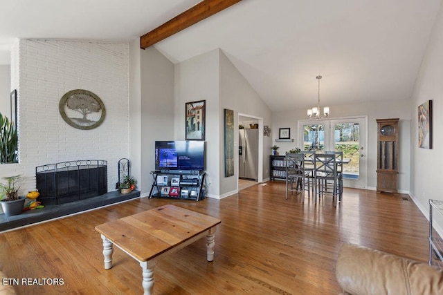 living area with beamed ceiling, high vaulted ceiling, wood finished floors, baseboards, and a brick fireplace