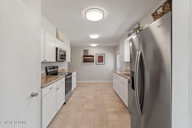 kitchen featuring white cabinets, light tile patterned floors, baseboards, and stainless steel appliances