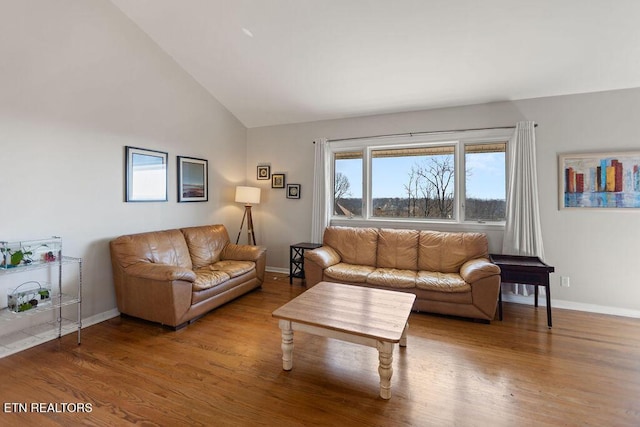 living area with baseboards, lofted ceiling, and wood finished floors