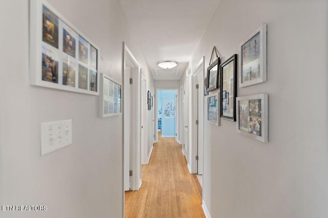 corridor with baseboards and light wood-style flooring