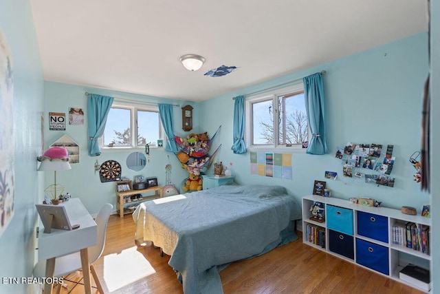 bedroom with multiple windows and wood finished floors