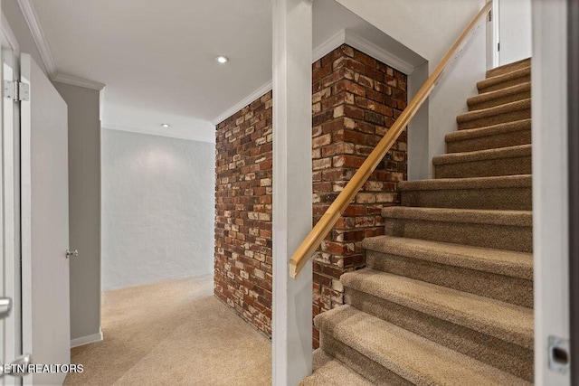 stairs with brick wall, carpet flooring, and ornamental molding