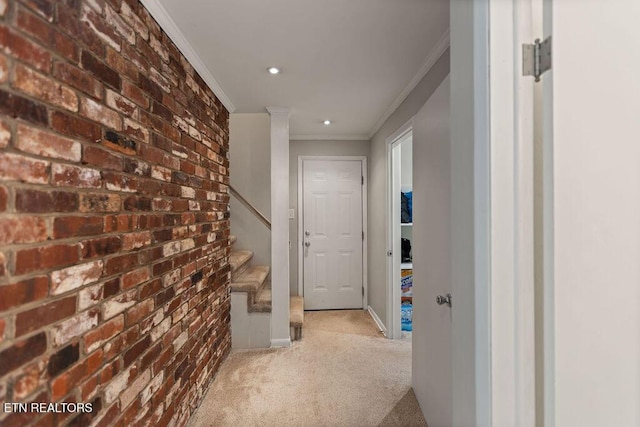 hallway with brick wall, baseboards, stairway, ornamental molding, and carpet floors