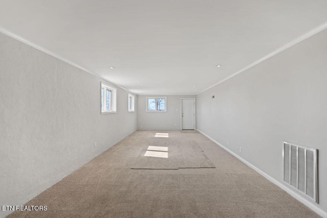 spare room featuring light carpet, visible vents, and ornamental molding