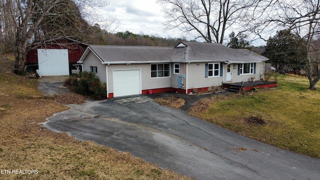 ranch-style home featuring a garage, metal roof, driveway, and a front lawn