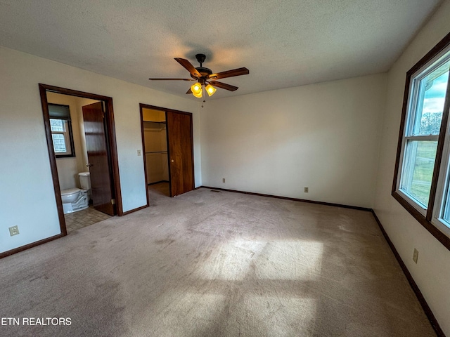 unfurnished bedroom with carpet, ensuite bathroom, ceiling fan, a textured ceiling, and baseboards