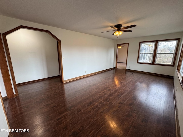 empty room with a ceiling fan, a textured ceiling, baseboards, and wood finished floors