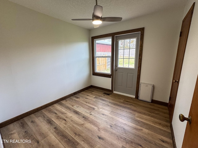 interior space featuring ceiling fan, a textured ceiling, baseboards, and wood finished floors