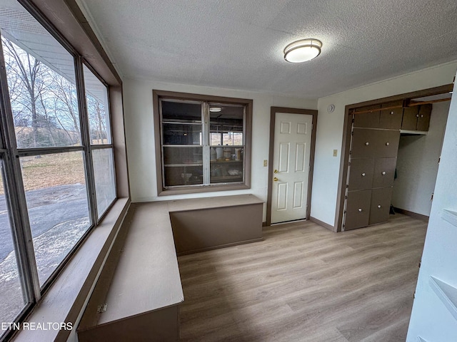 interior space featuring a textured ceiling, baseboards, and wood finished floors