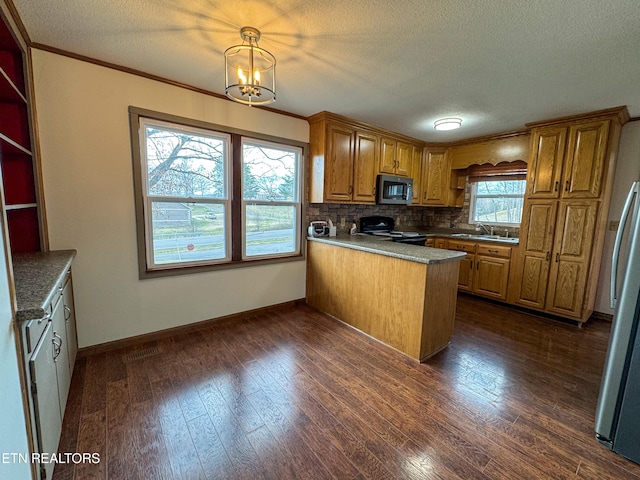 kitchen with dark wood finished floors, stainless steel appliances, brown cabinetry, a sink, and a peninsula