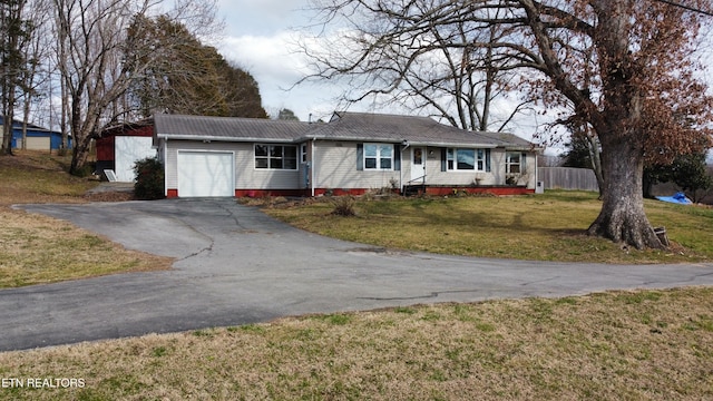 ranch-style house featuring an attached garage, metal roof, a front lawn, and aphalt driveway