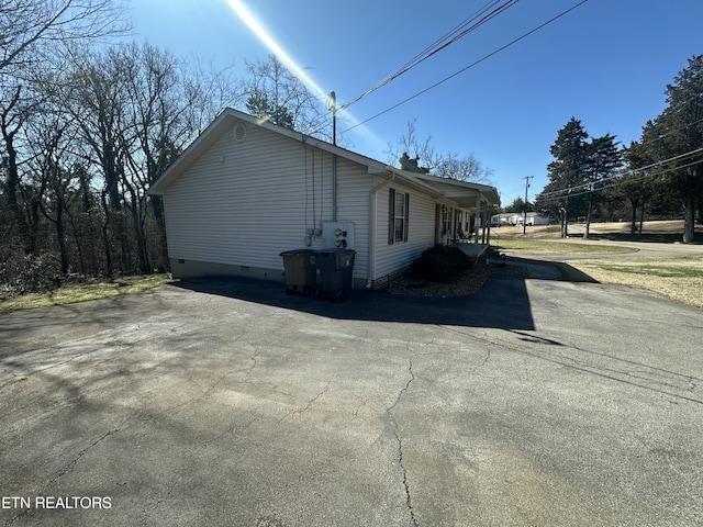 view of property exterior featuring crawl space and aphalt driveway