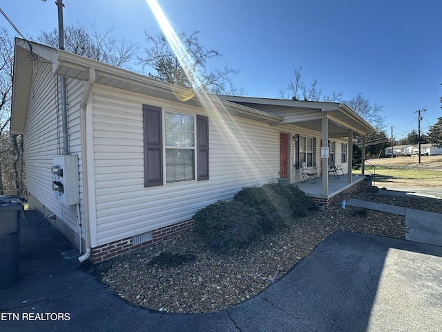 view of side of property featuring crawl space and covered porch