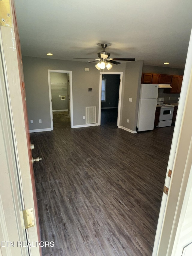 unfurnished living room featuring dark wood-style floors, ceiling fan, visible vents, and baseboards