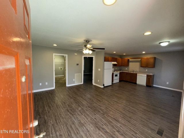 unfurnished living room with dark wood-style flooring, a sink, a ceiling fan, visible vents, and baseboards