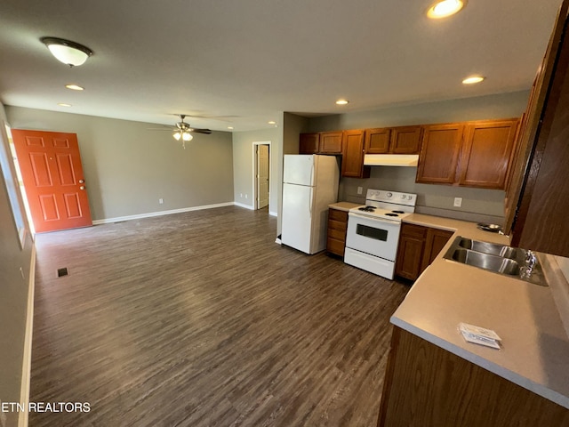 kitchen with recessed lighting, dark wood-type flooring, a sink, white appliances, and under cabinet range hood