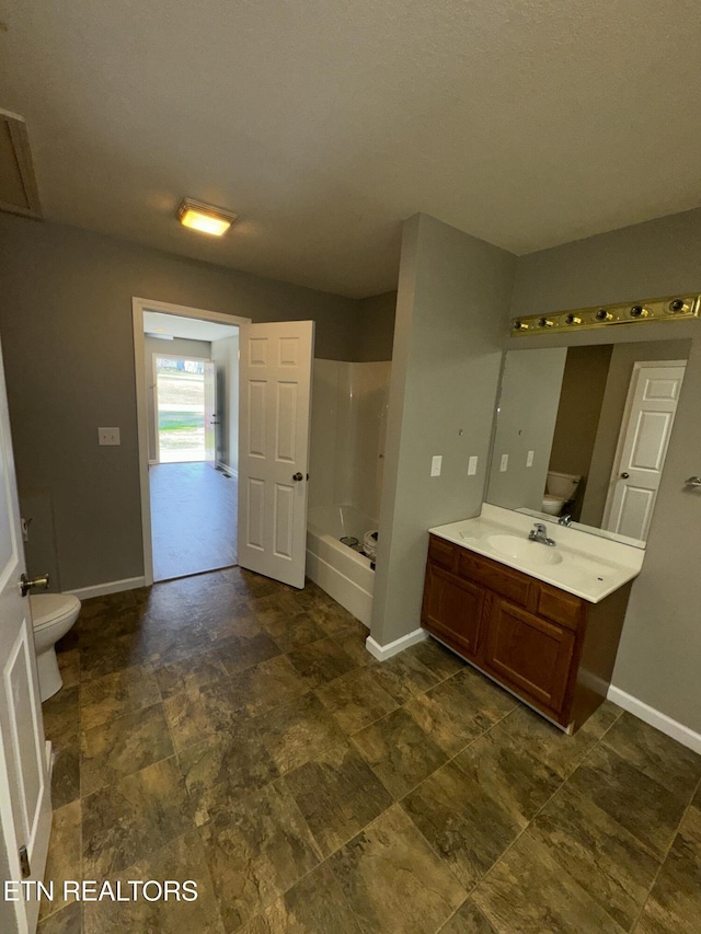 bathroom with toilet, baseboards, a bath, and vanity