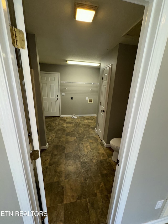 bathroom with stone finish floor, toilet, and baseboards