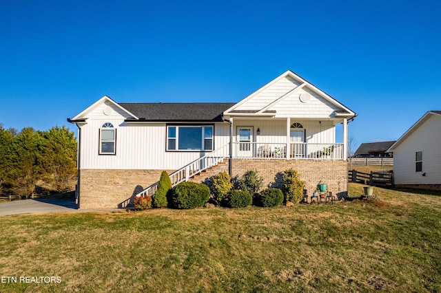 ranch-style house featuring covered porch, brick siding, and a front lawn