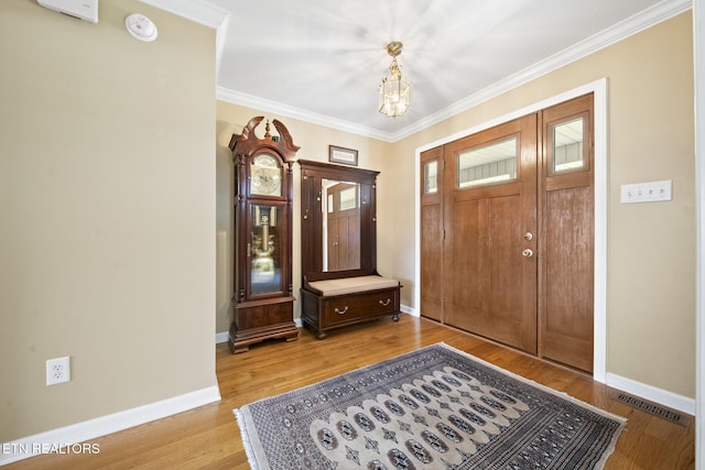 entryway featuring visible vents, baseboards, ornamental molding, light wood-style floors, and a notable chandelier