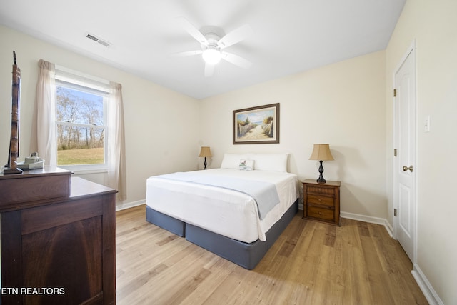 bedroom featuring ceiling fan, visible vents, light wood-type flooring, and baseboards