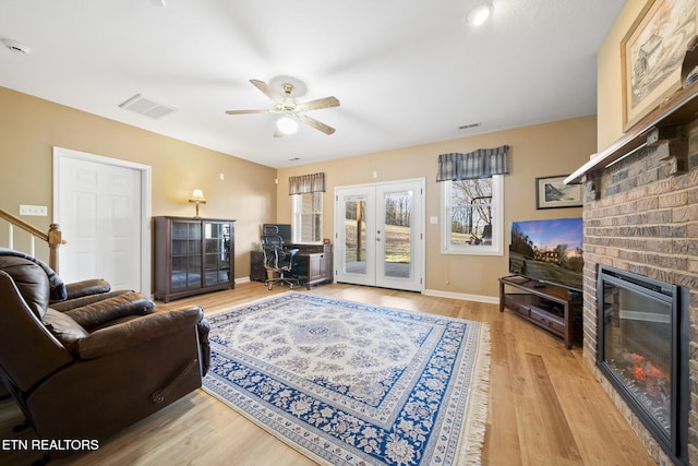 living room with visible vents, light wood-style flooring, french doors, and a fireplace