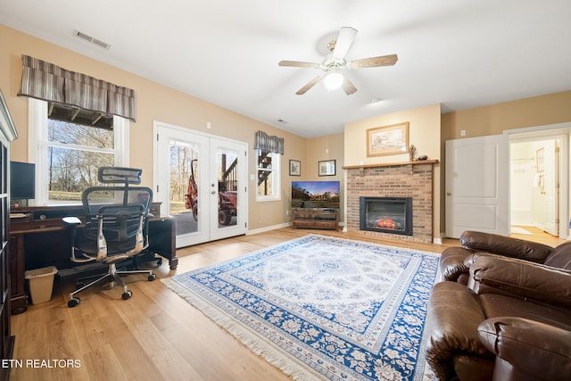 office featuring visible vents, french doors, a fireplace, wood finished floors, and a ceiling fan