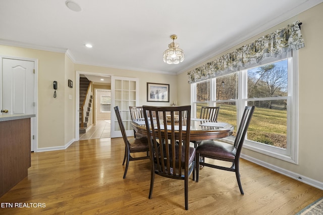 dining room featuring wood finished floors, stairs, baseboards, and ornamental molding