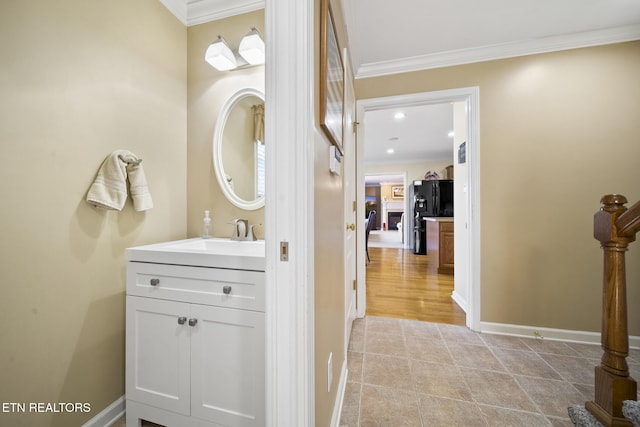 bathroom with baseboards, vanity, crown molding, and tile patterned flooring