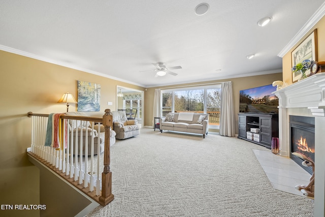 carpeted living area with a fireplace with flush hearth, crown molding, and ceiling fan