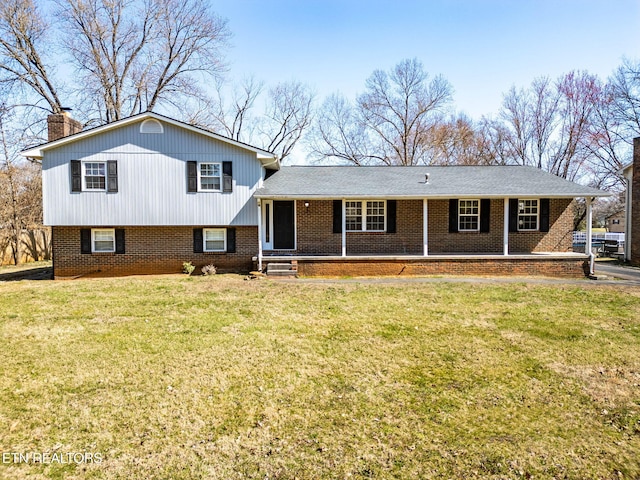 tri-level home featuring a front yard, a porch, brick siding, and a chimney