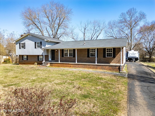 split level home with brick siding, driveway, a porch, and a front lawn