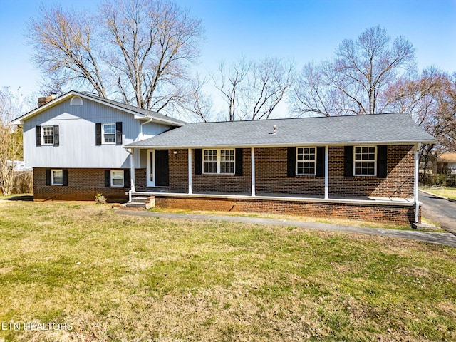 split level home with brick siding, covered porch, a chimney, and a front yard