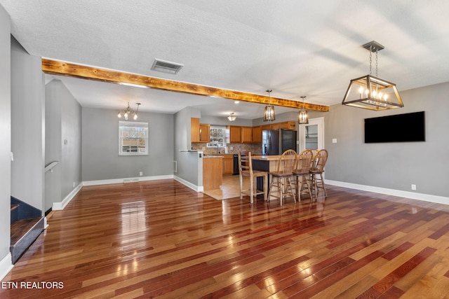 interior space featuring baseboards, visible vents, wood-type flooring, and beam ceiling