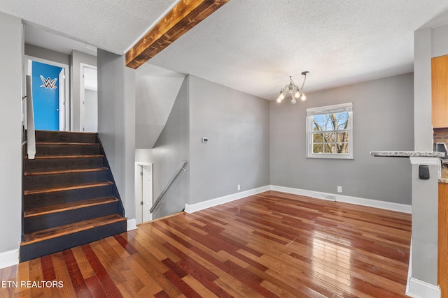 stairway with visible vents, baseboards, hardwood / wood-style floors, an inviting chandelier, and a textured ceiling