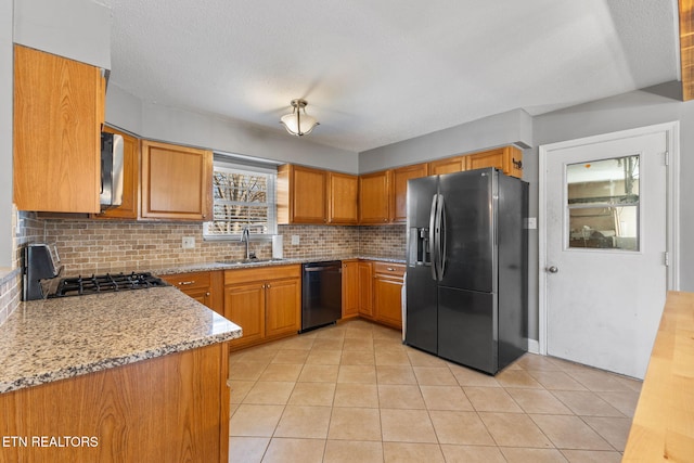 kitchen with brown cabinets, black appliances, a sink, light tile patterned floors, and decorative backsplash