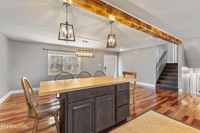 kitchen featuring a breakfast bar, beamed ceiling, wood finished floors, and butcher block counters