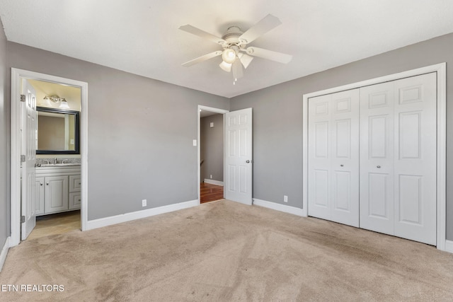 unfurnished bedroom with baseboards, ensuite bath, a sink, a closet, and light carpet