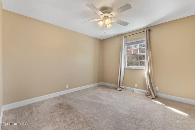 carpeted spare room featuring a textured ceiling, baseboards, visible vents, and ceiling fan