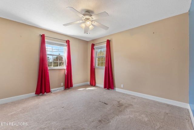 carpeted empty room with visible vents, baseboards, a textured ceiling, and a ceiling fan