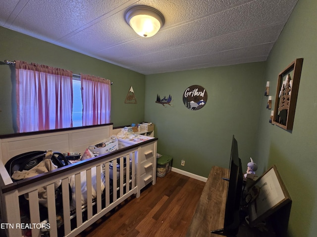 bedroom featuring a textured ceiling, baseboards, and wood finished floors